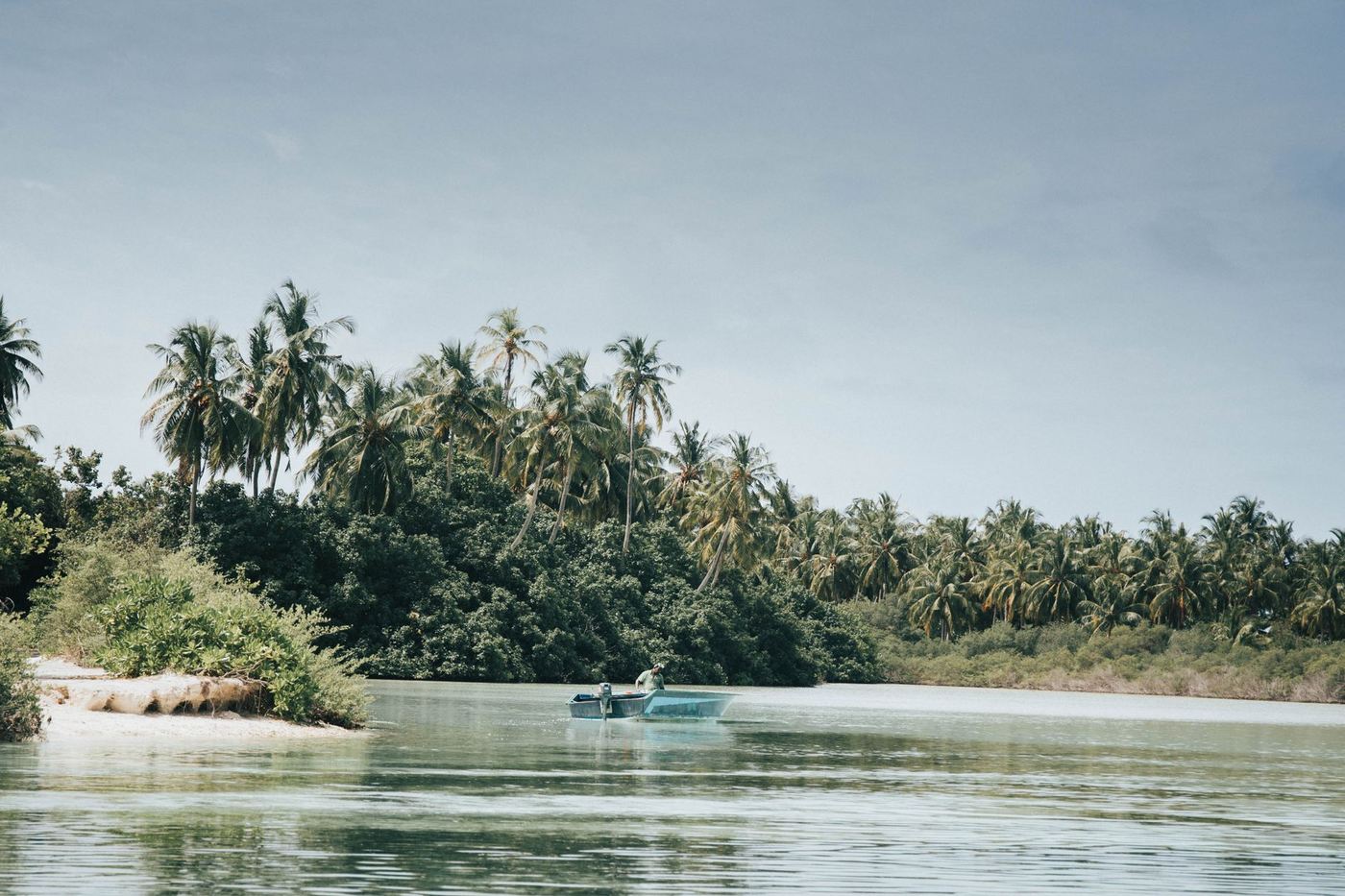 Barque sur un lagon bordé de cocotiers
