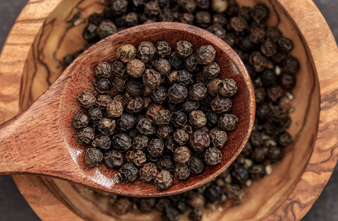 Grains de poivre dans une cuillère en bois