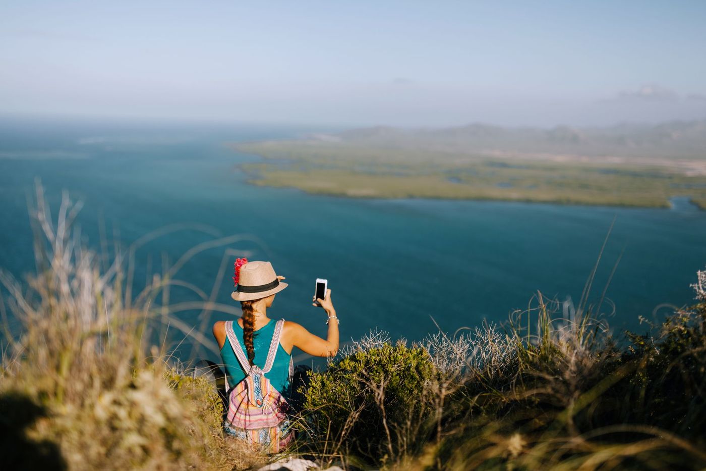 Traveler photographing a lagoon from a hilltop